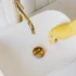 weißes Waschbecken, das von einer Hand in gelbem Gummihandschuh geputzt wird