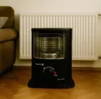 Petroleumofen Ein Petroleumofen steht vor einer nicht funktionierenden Heizung im Innenraum als Notfallheizung