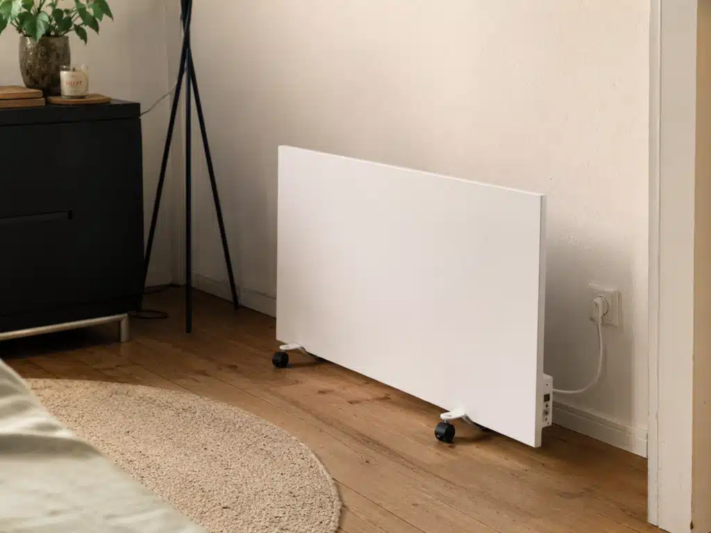 - Infrarotheizung Standgerät: Weiße mobile Infrarotheizung auf Rollen, eingesteckt in einem gemütlichen Wohnzimmer.