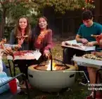 Feuerschale mit Funkenschutz Gruppe junger Menschen sitzt im Garten um eine kompakte Feuerschale mit Funkenschutz und isst gemeinsam Pizza.