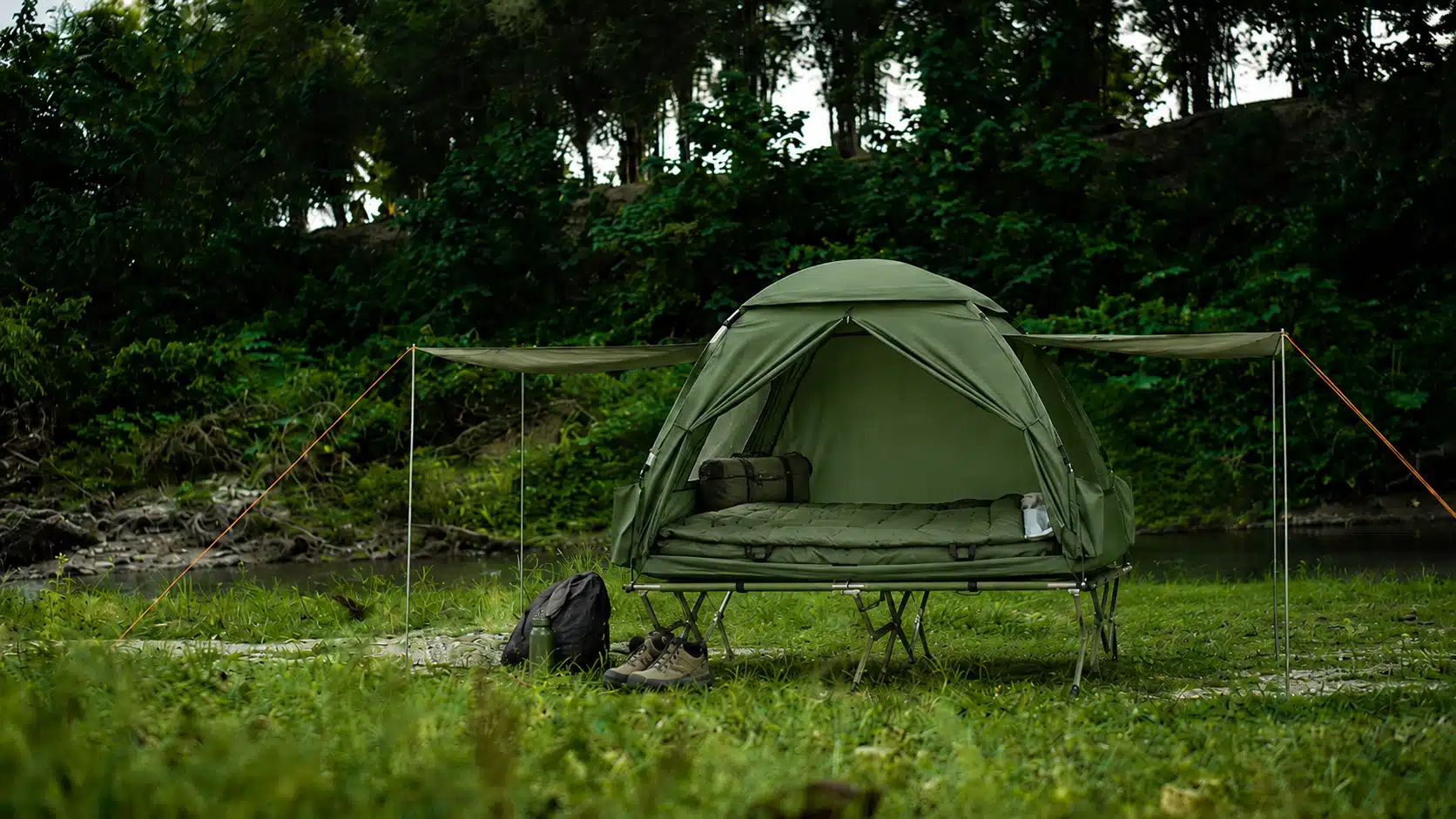Feldbett mit Zelt für 2 Personen beim Camping im Grünen