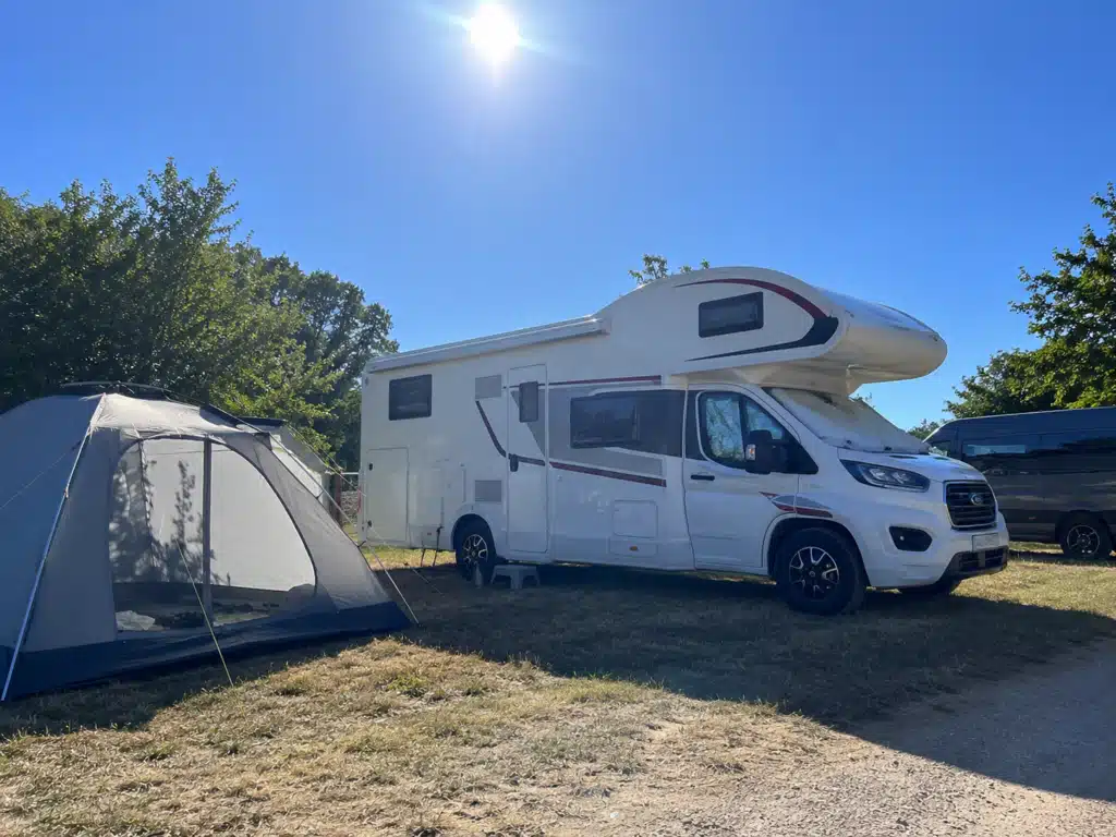 - Camping bei Hitze mit Wohnmobil und Zelt in der prallen Sonne auf einem Campingplatz
