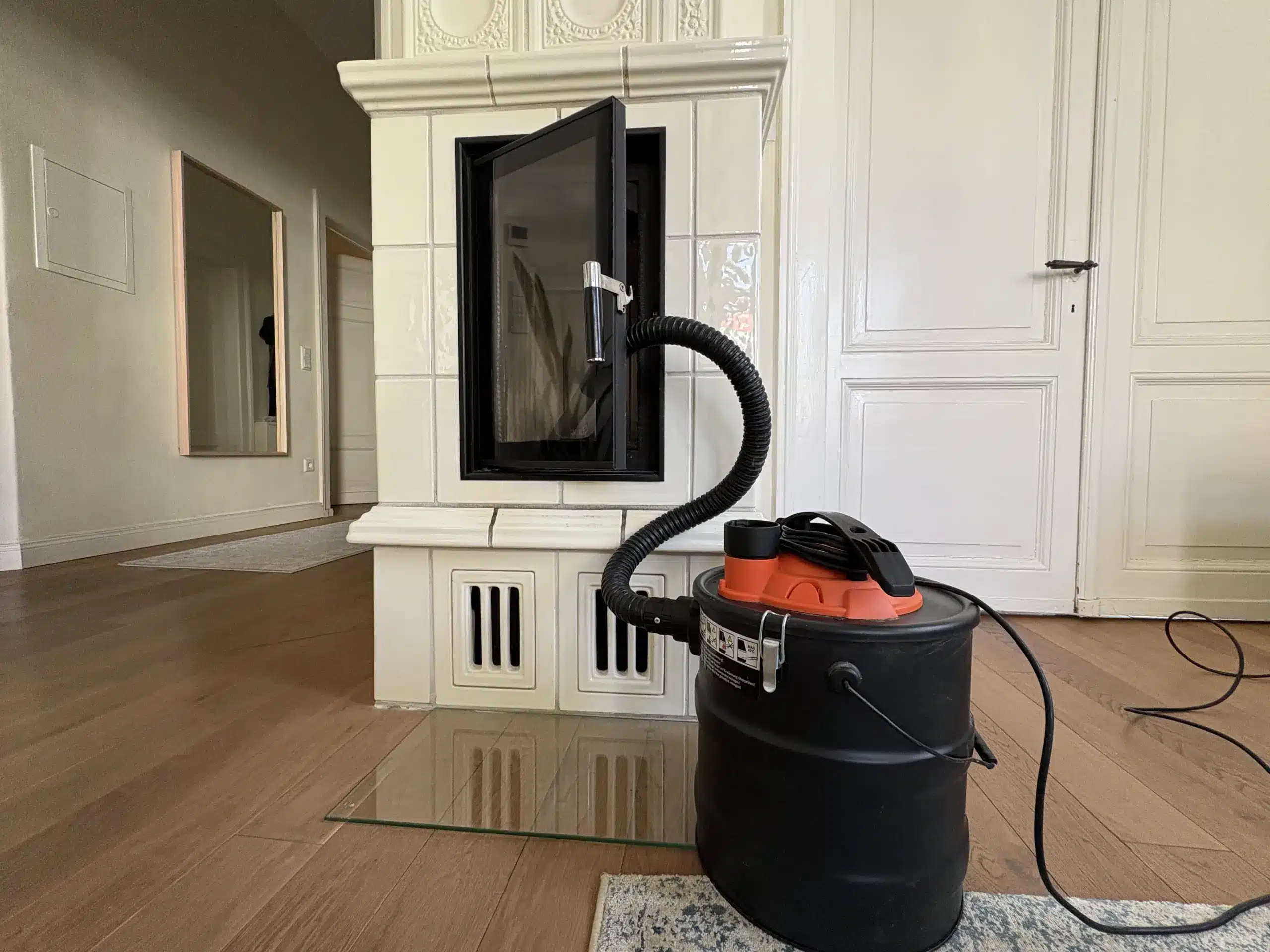 Aschesauger Filter reinigen mit Aschesauger und Saugschlauch vor einem Kaminofen